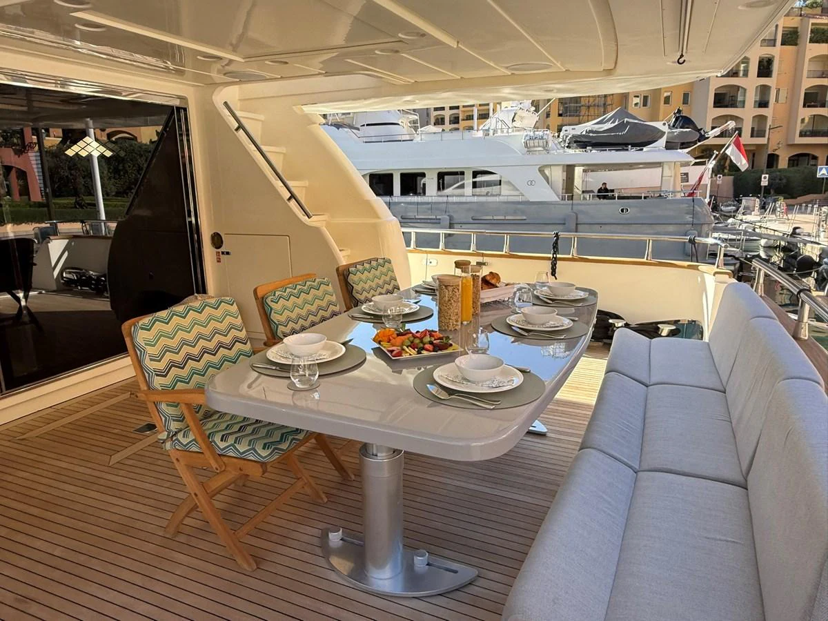 The aft deck features a stylish dining area with a table set for a meal, surrounded by comfortable seating. aboard TIME OUT TOGETHER Yacht for Sale