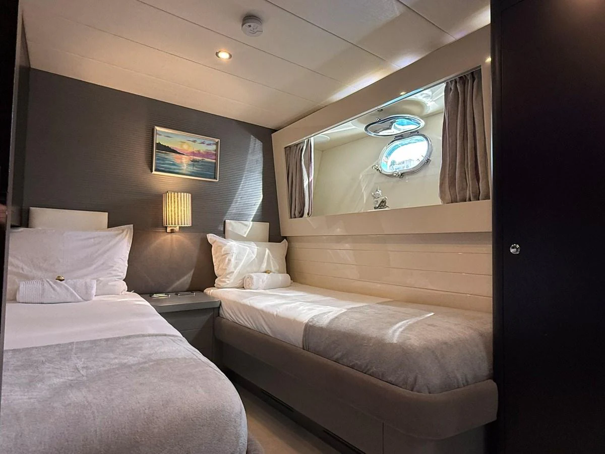 A cozy twin stateroom featuring two single beds and a porthole window. aboard TIME OUT TOGETHER Yacht for Sale