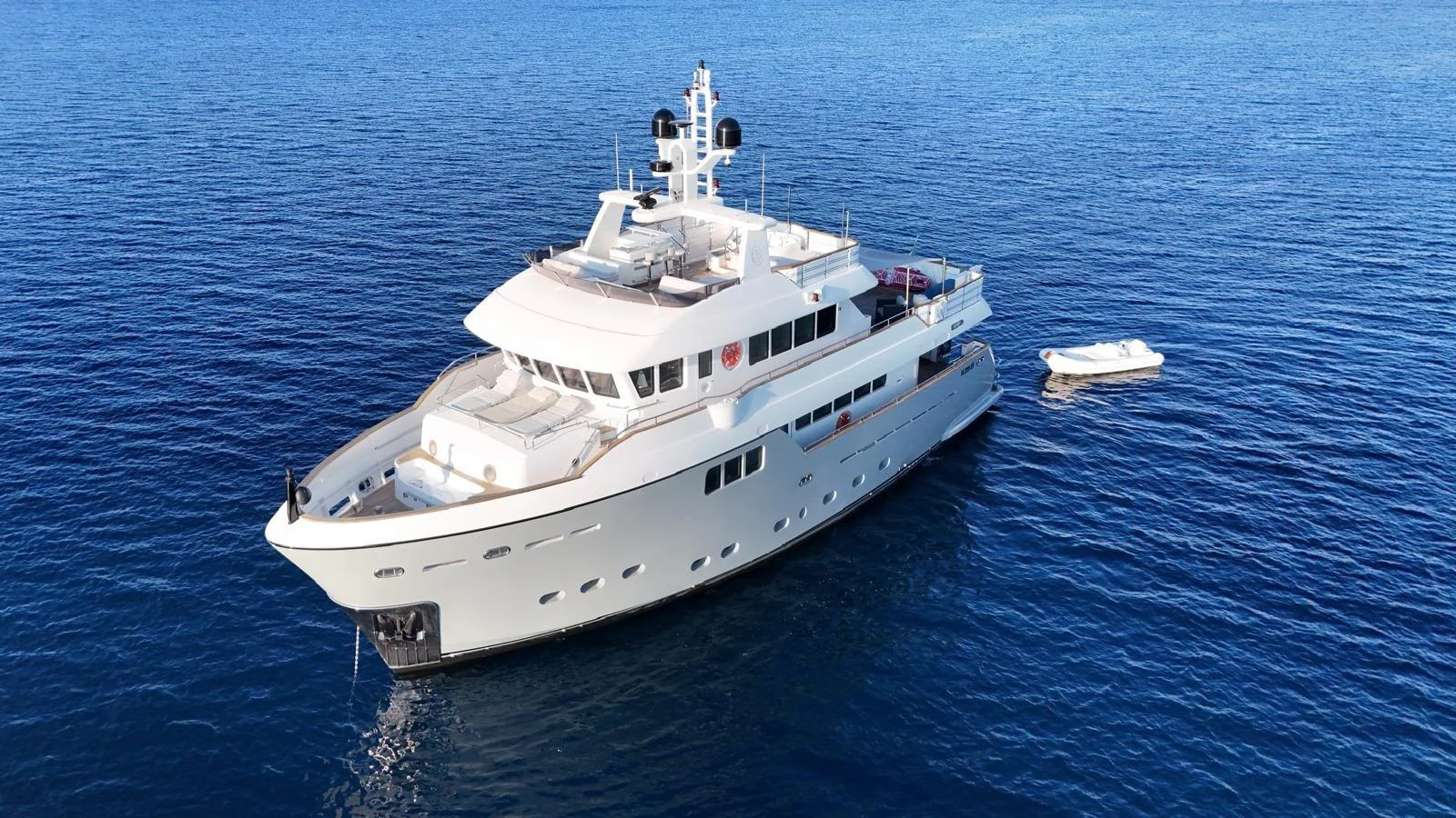 A luxurious yacht is anchored in calm blue waters, showcasing its sleek design and spacious decks. aboard GRANIL Yacht for Sale
