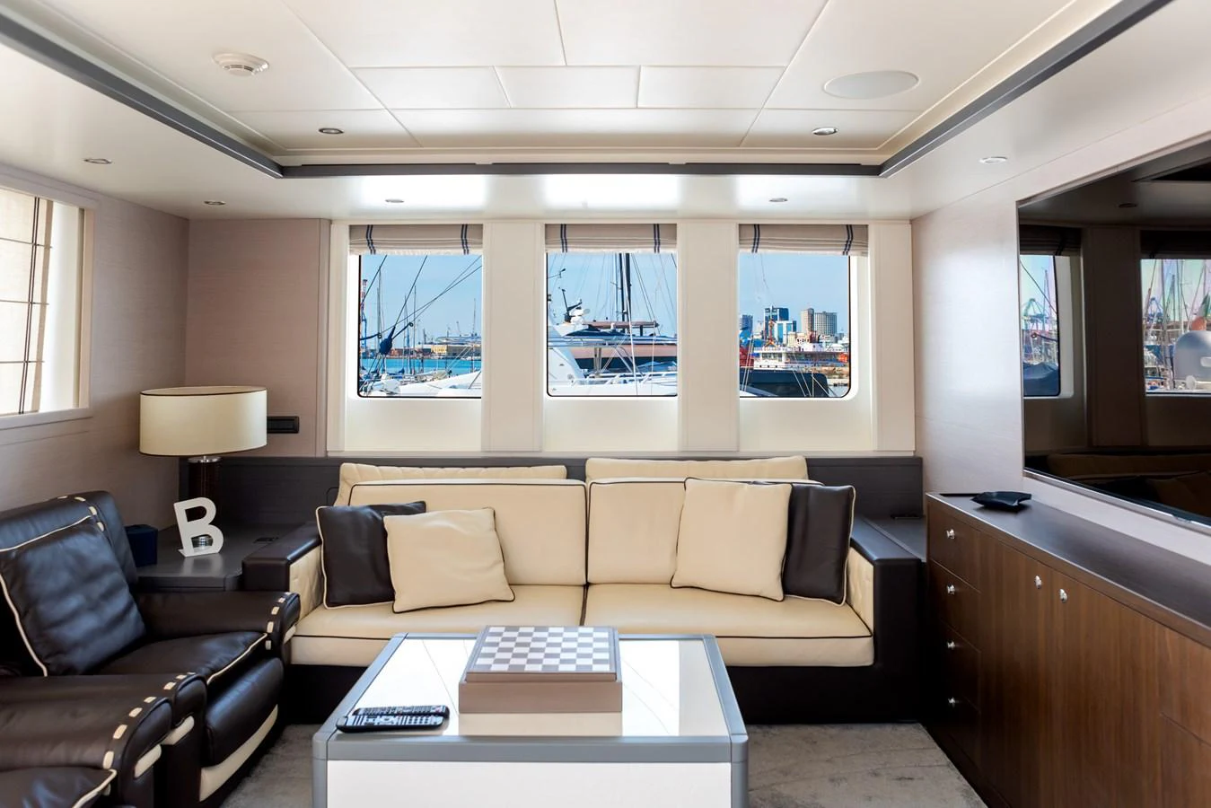 The yacht's salon features a comfortable seating area with large windows offering a view of the marina. aboard GRANIL Yacht for Sale