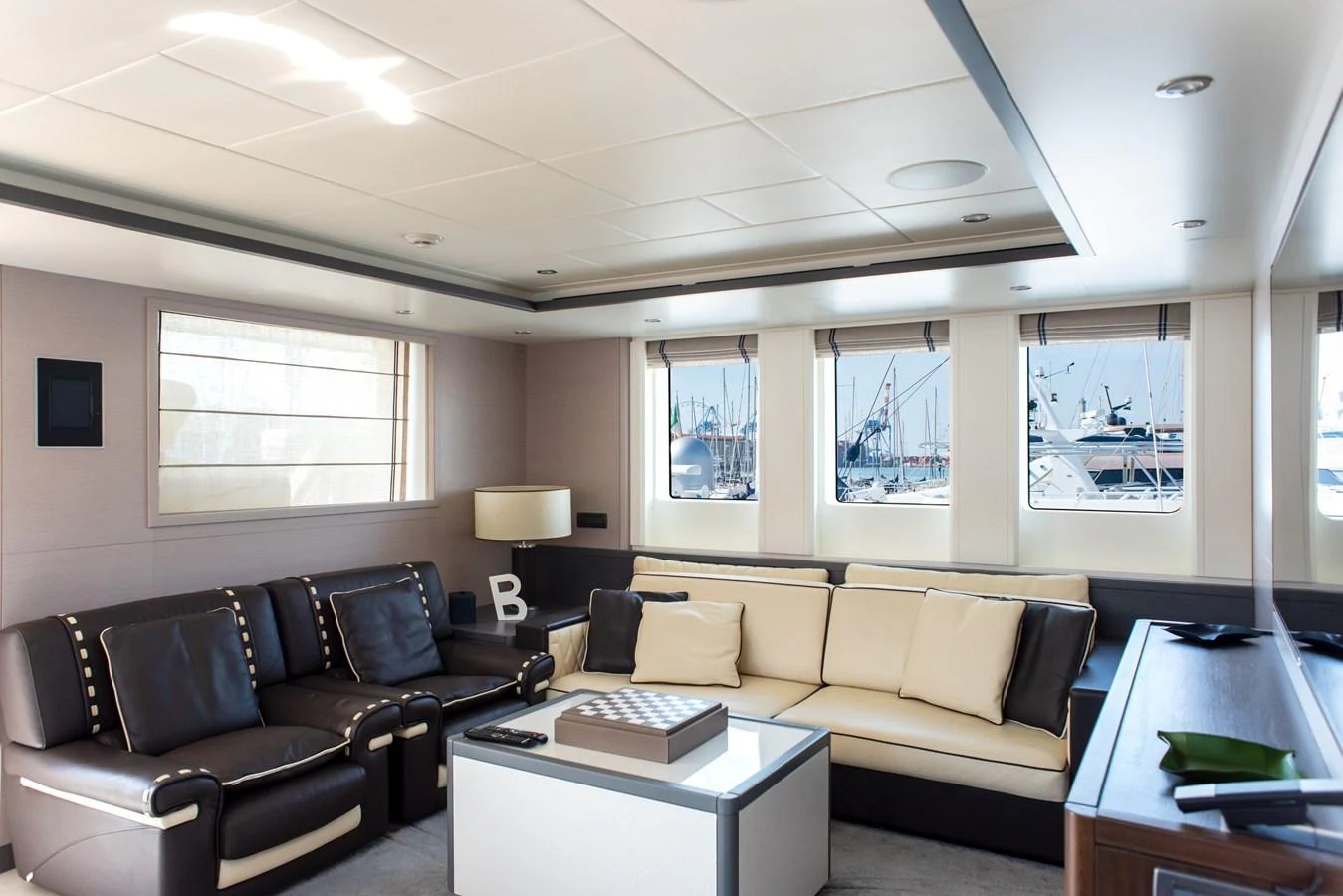 The salon features plush seating and large windows, offering a comfortable and inviting space with views of the marina. aboard GRANIL Yacht for Sale