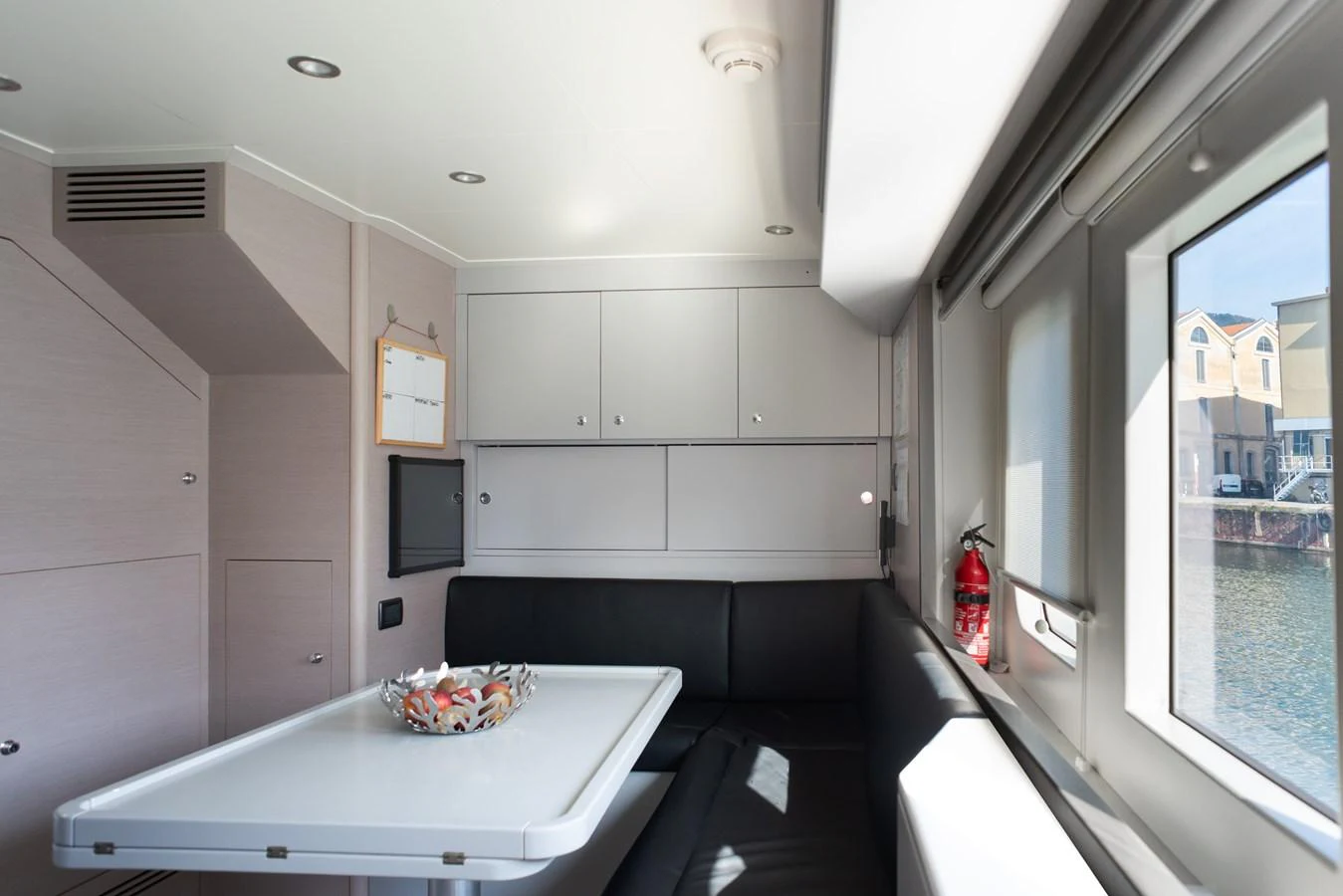 The yacht's dining area features a sleek table and comfortable seating with ample natural light from large windows. aboard GRANIL Yacht for Sale