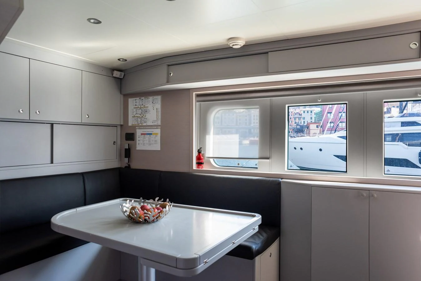 A cozy dining area with a table and seating, featuring windows with a view of the marina. aboard GRANIL Yacht for Sale