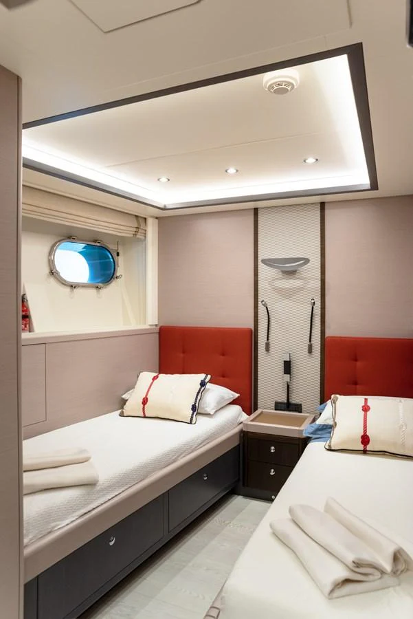 The guest cabin features twin beds with modern decor and a porthole for natural light. aboard GRANIL Yacht for Sale