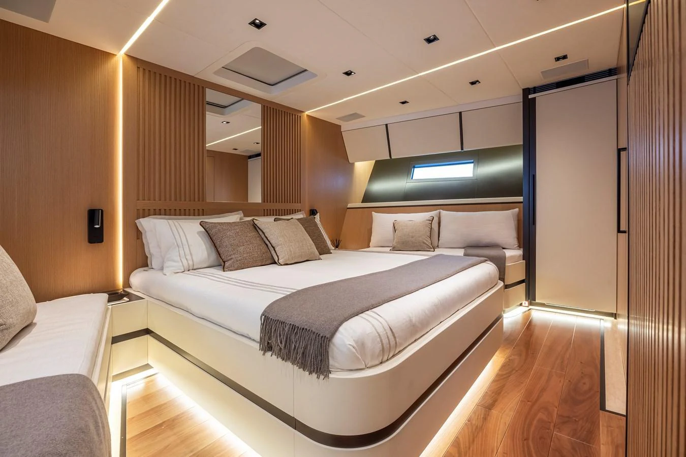 The stateroom features a luxurious bed with elegant wood paneling and ambient lighting. aboard SEXY ME Yacht for Sale