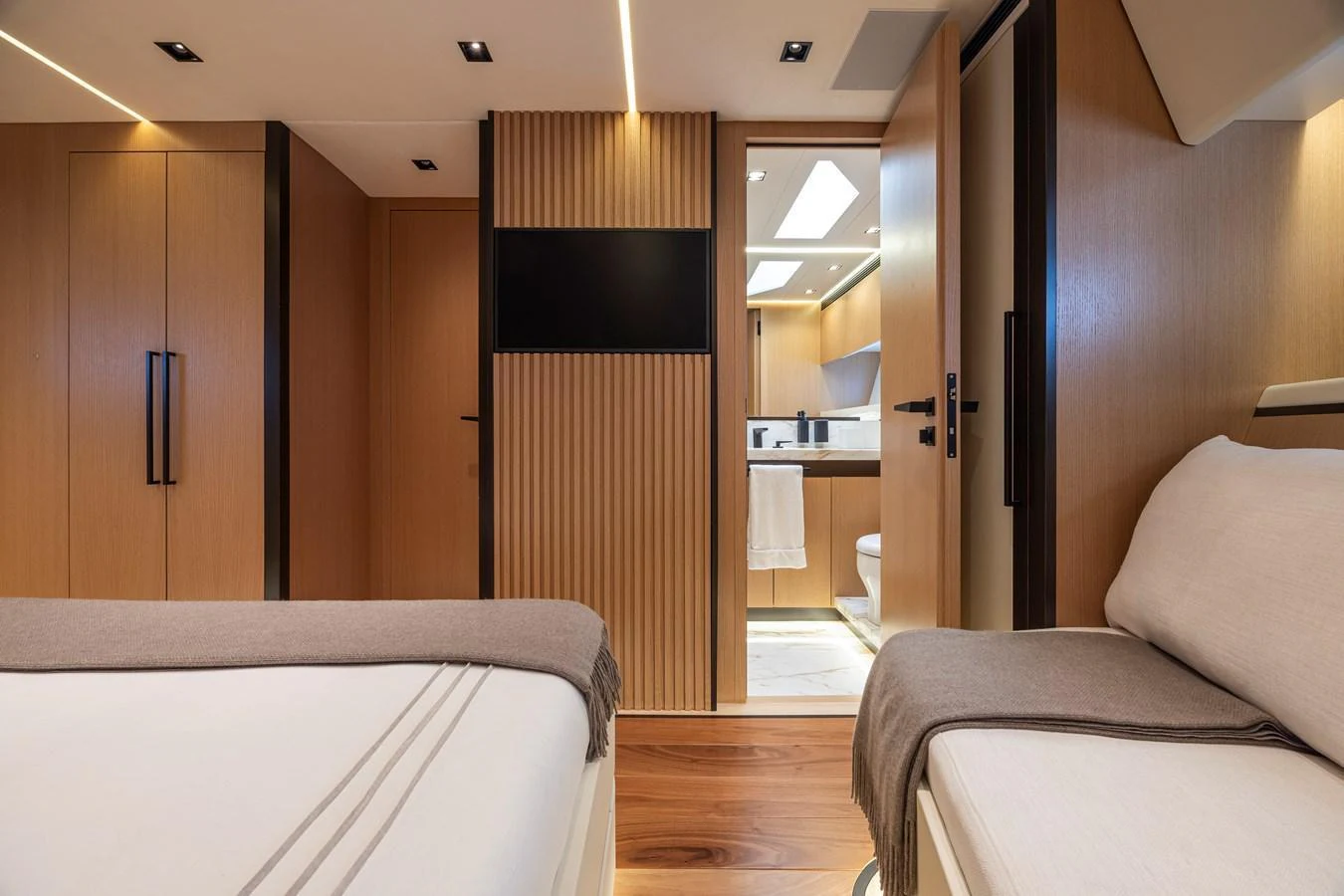 The yacht's interior features a cozy and modern stateroom with warm wood finishes and comfortable bedding. aboard SEXY ME Yacht for Sale
