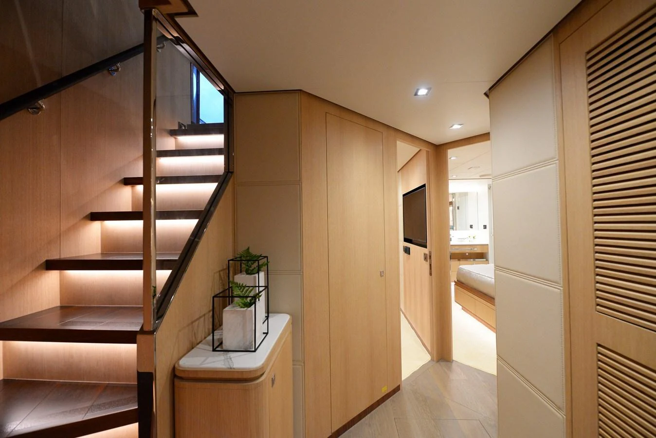 The image showcases a modern interior hallway with a staircase and a glimpse into a bedroom area. aboard AQUA LIFE Yacht for Sale