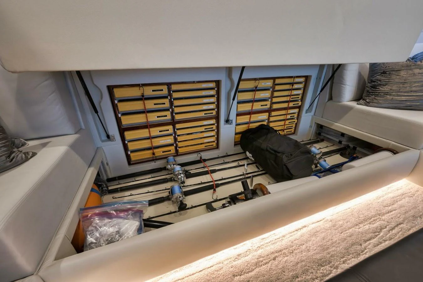 The image showcases a well-organized storage compartment with fishing rods and tackle boxes. aboard NIKKI BELLA Yacht for Sale