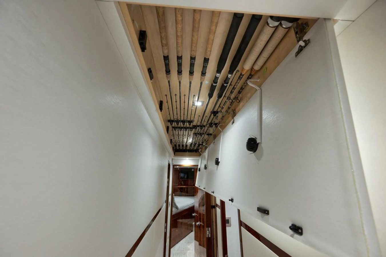 A hallway with fishing rods neatly stored on the ceiling, leading to a cozy cabin area. aboard NIKKI BELLA Yacht for Sale