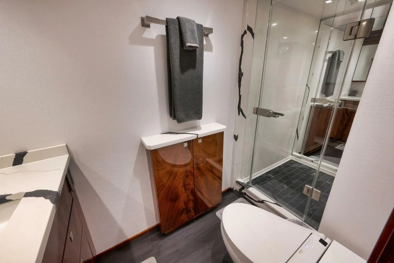 A modern yacht bathroom featuring sleek wood cabinetry and a glass-enclosed shower. aboard NIKKI BELLA Yacht for Sale