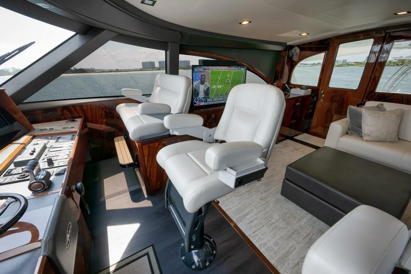 The yacht's helm features luxurious white seating and advanced navigation controls, with a view of the water through large windows. aboard NIKKI BELLA Yacht for Sale