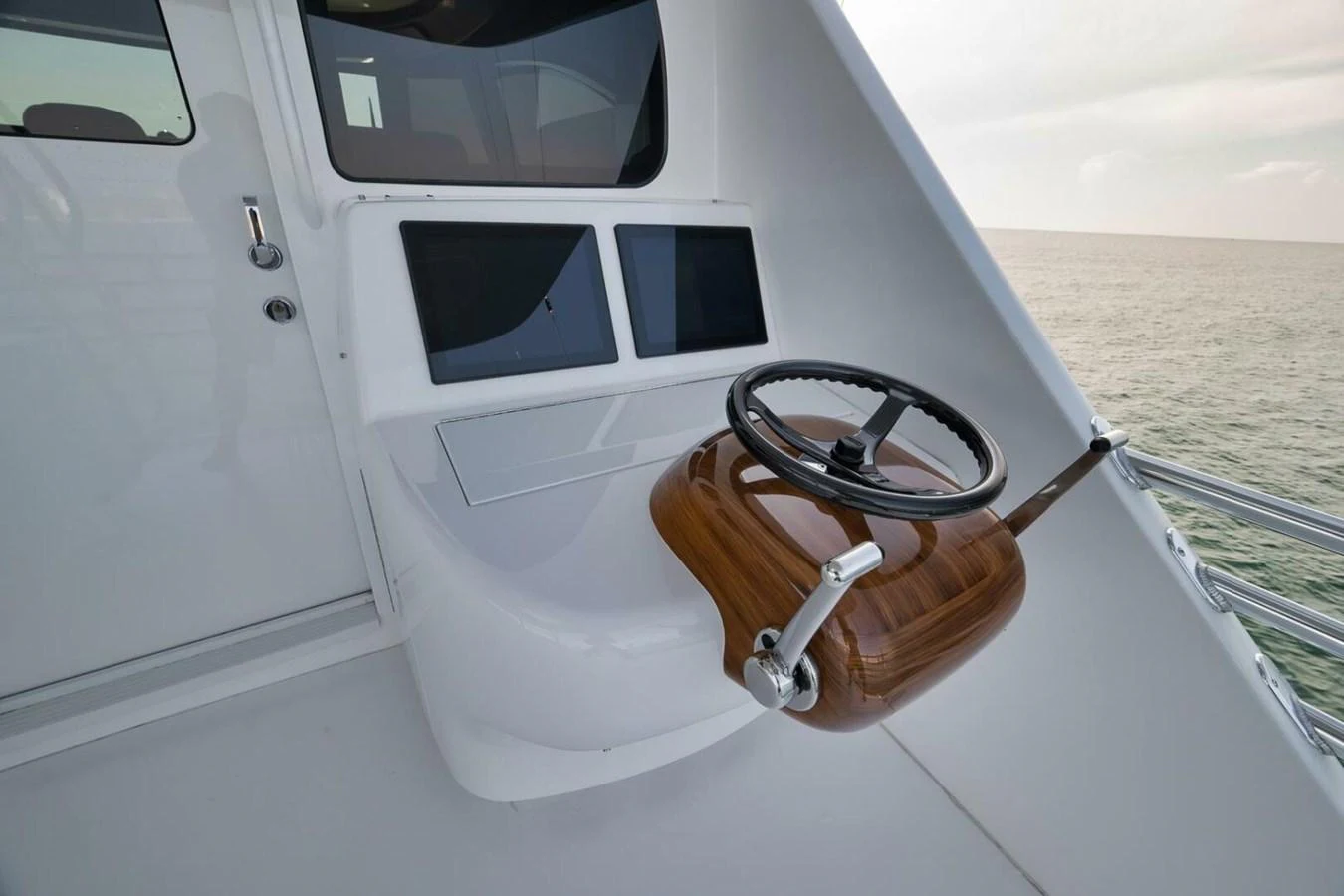 The image showcases a sleek helm station with dual screens and a polished wooden steering wheel. aboard NIKKI BELLA Yacht for Sale