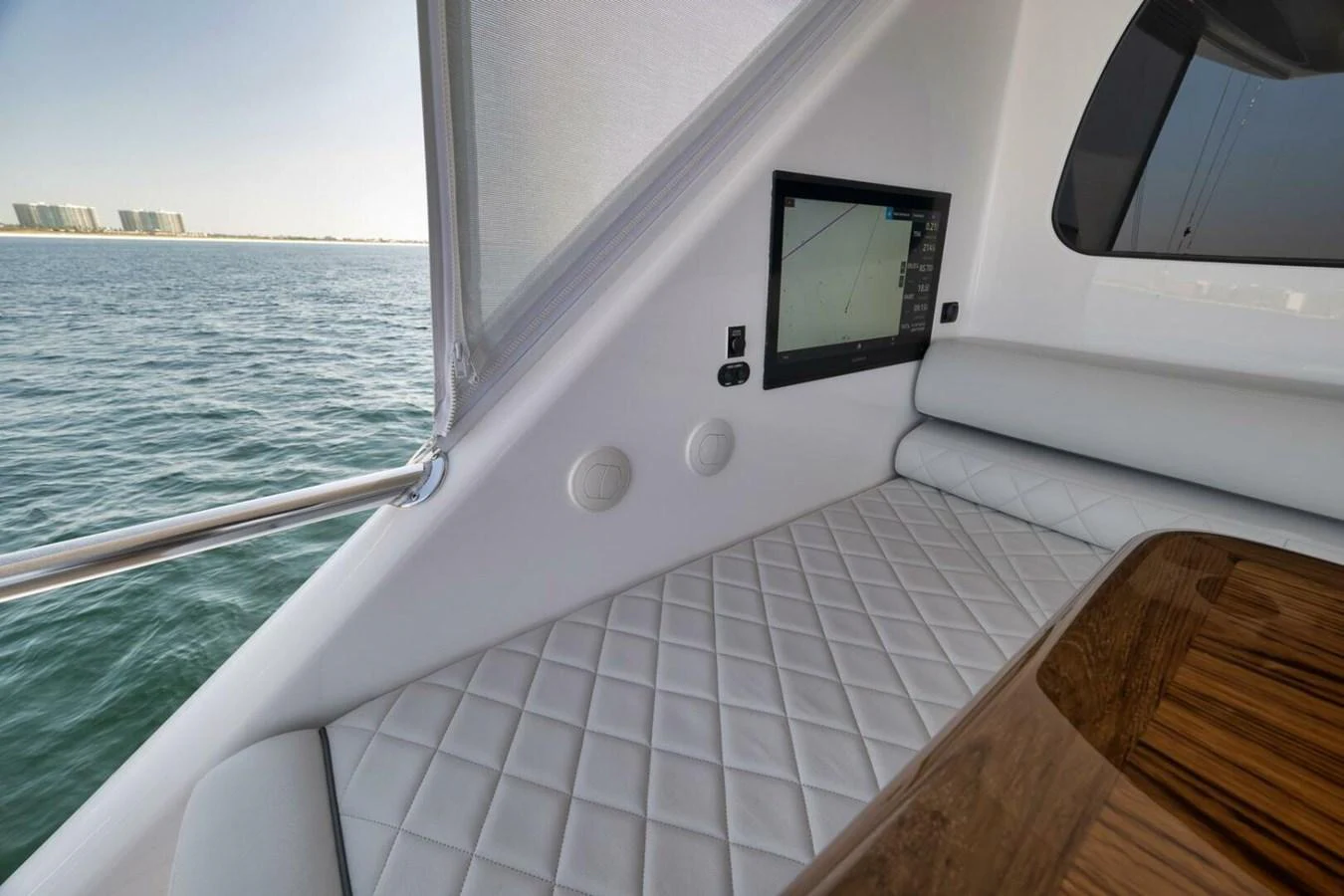 A cozy interior seating area with a quilted cushion and a built-in screen, offering a view of the water outside. aboard NIKKI BELLA Yacht for Sale