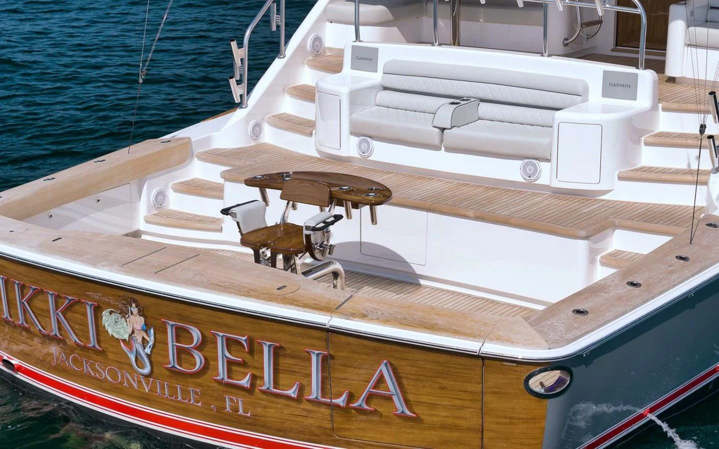 The aft deck features a spacious seating area with a wooden table, perfect for outdoor relaxation and dining. aboard NIKKI BELLA Yacht for Sale