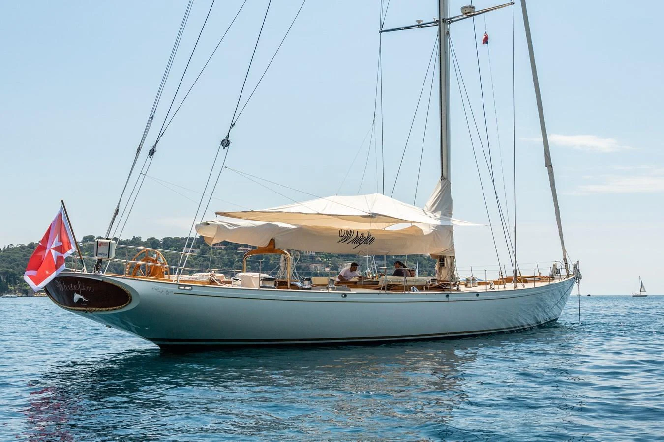 A classic sailing yacht with elegant lines and a spacious deck, anchored in calm waters. aboard WHITEFIN Yacht for Sale