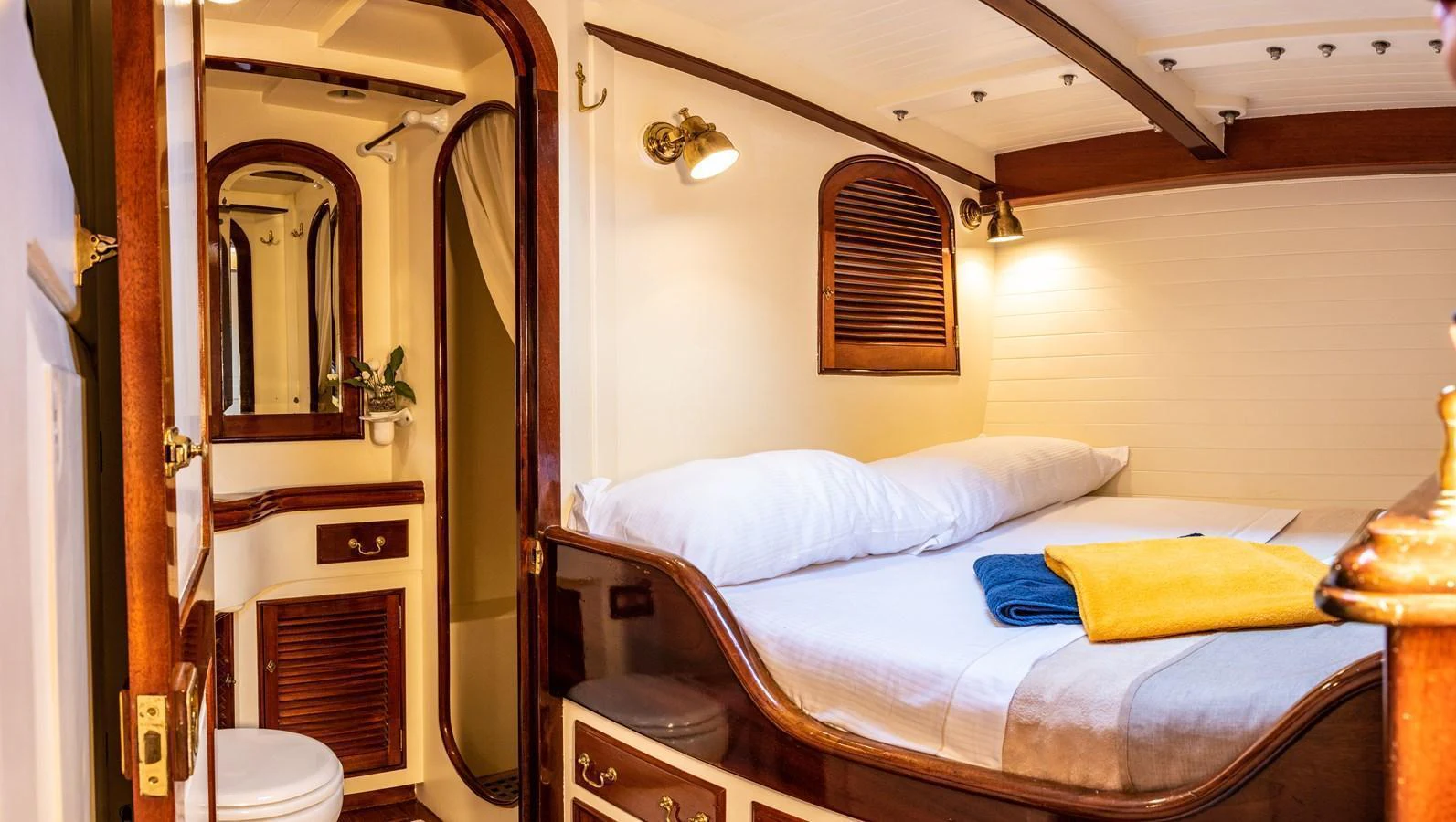 The cozy guest cabin features a comfortable bed, warm lighting, and classic wooden accents. aboard WHITEFIN Yacht for Sale