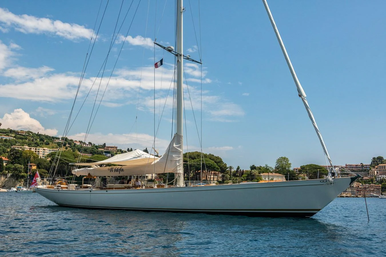 A sleek sailing yacht glides gracefully on the water against a scenic coastal backdrop. aboard WHITEFIN Yacht for Sale