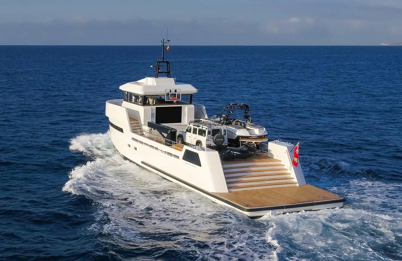 A sleek yacht cruises through the open sea, showcasing its expansive aft deck with vehicles onboard. aboard 27 YXT Yacht for Sale
