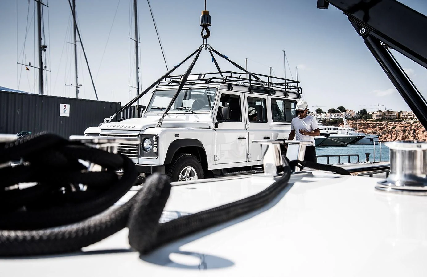 A yacht is being loaded with a white Land Rover Defender at the marina. aboard 27 YXT Yacht for Sale