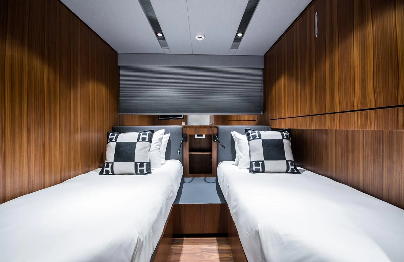 A cozy twin stateroom with modern wooden paneling and stylish bedding. aboard 27 YXT Yacht for Sale