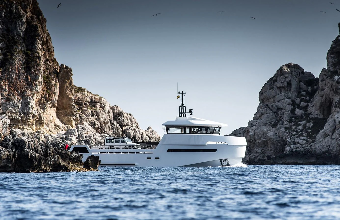 A sleek yacht navigates through rocky coastal waters, showcasing its modern design. aboard 27 YXT Yacht for Sale