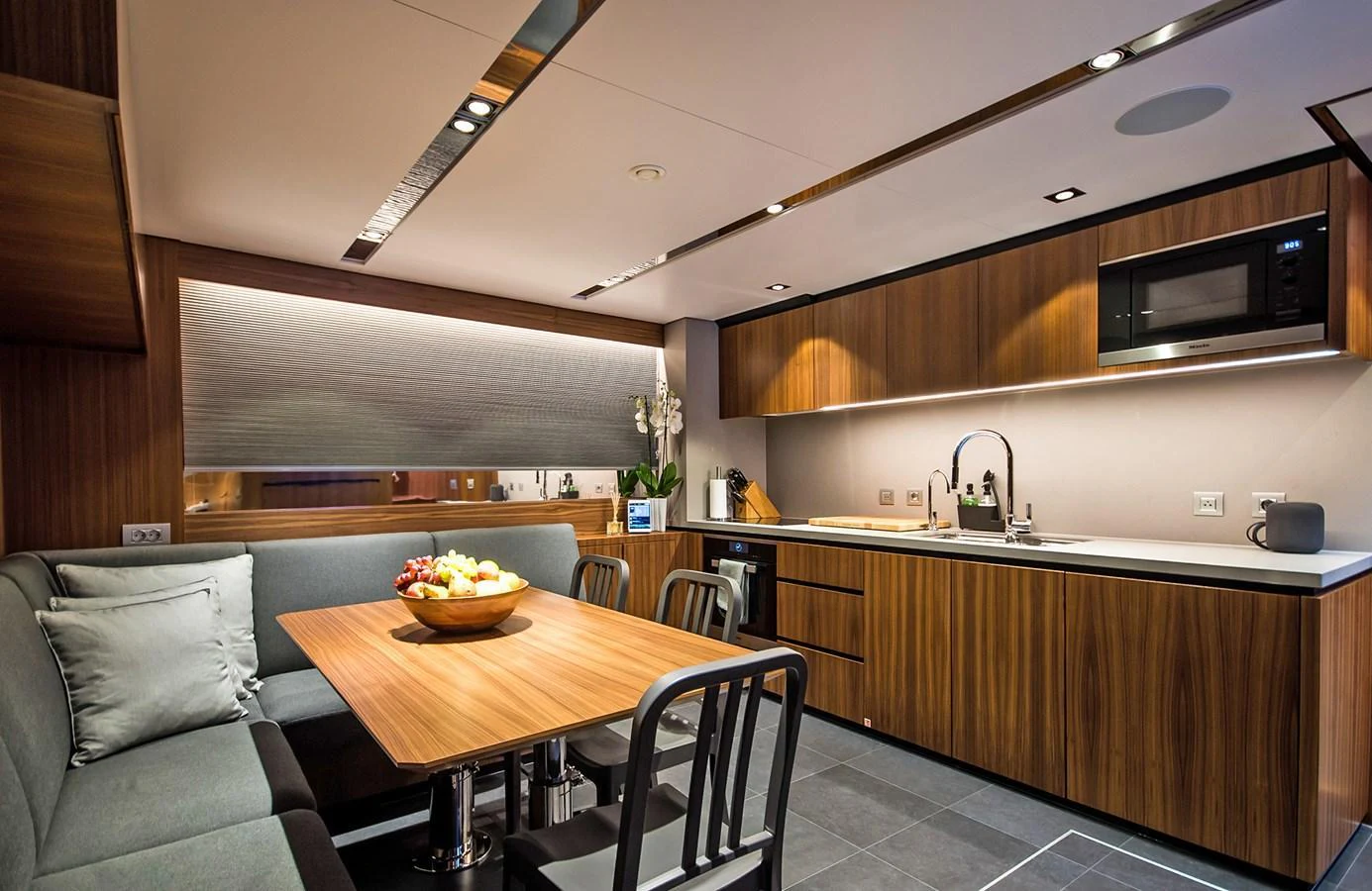 The galley features modern wooden cabinetry, a cozy dining area, and sleek appliances. aboard 27 YXT Yacht for Sale