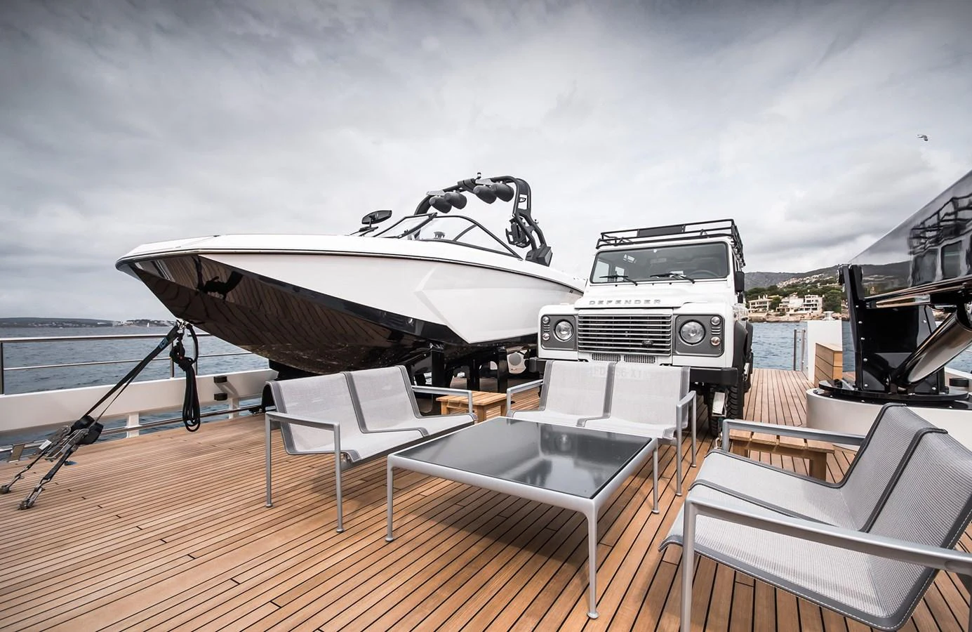 The aft deck features a sleek tender and a rugged off-road vehicle, complemented by modern outdoor seating. aboard 27 YXT Yacht for Sale