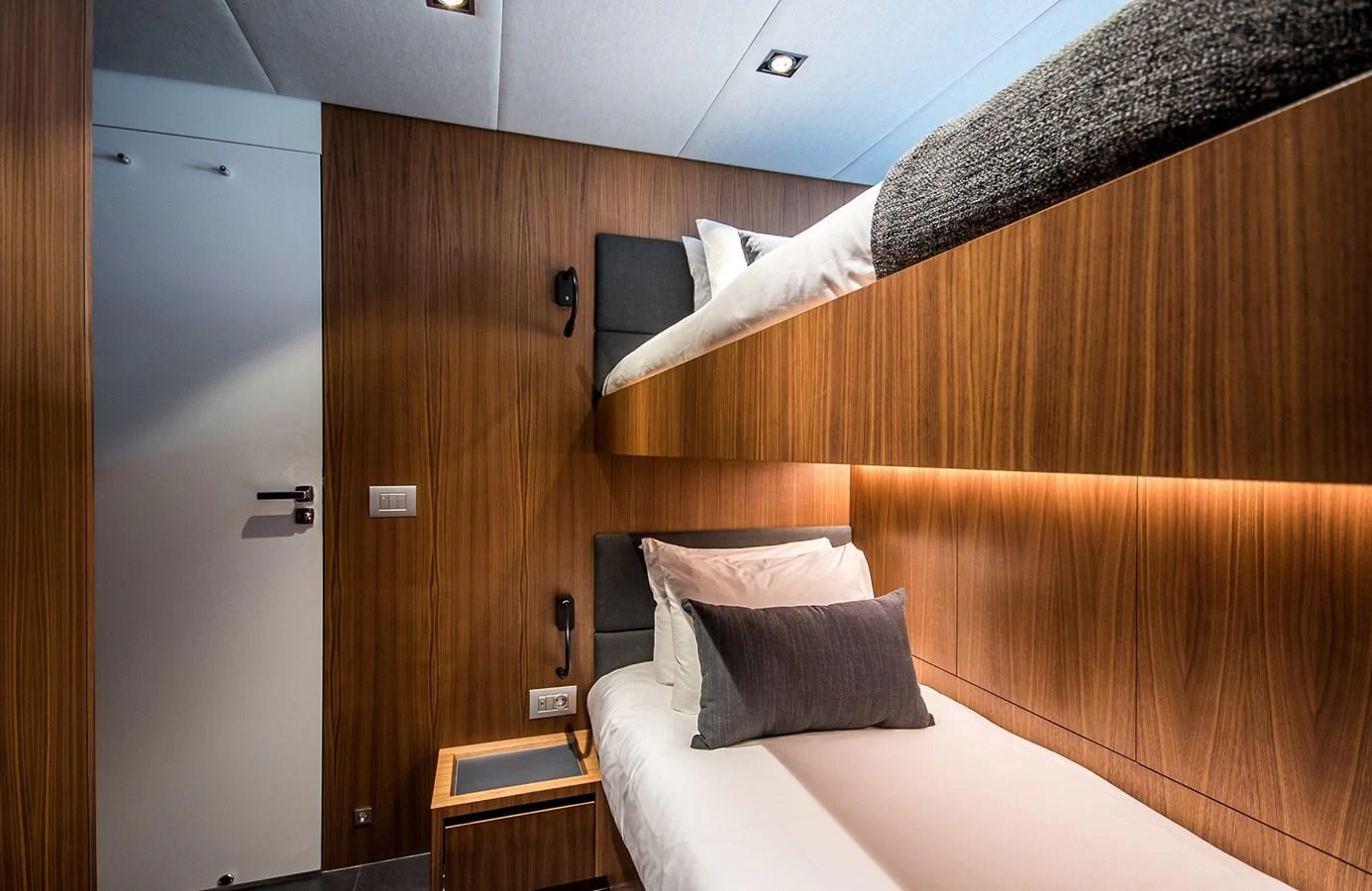 The guest stateroom features modern wood paneling and comfortable bedding in a cozy, well-lit space. aboard 27 YXT Yacht for Sale