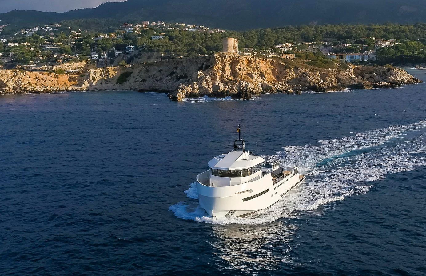 A sleek yacht cruises along a scenic coastline with a historic tower in the background. aboard 27 YXT Yacht for Sale