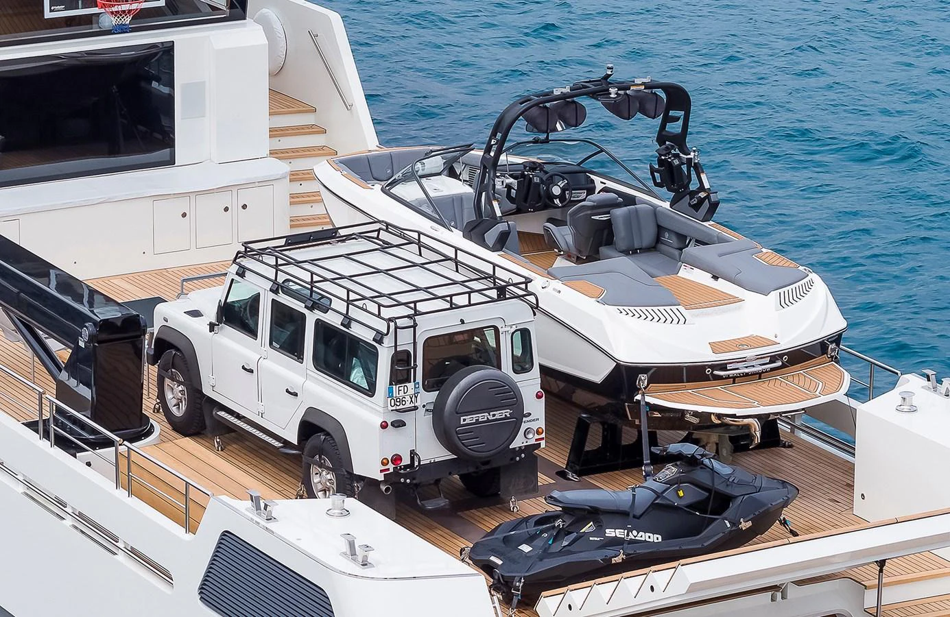The yacht's deck showcases a luxurious setup with a Land Rover, a speedboat, and a jet ski, ready for adventure. aboard 27 YXT Yacht for Sale