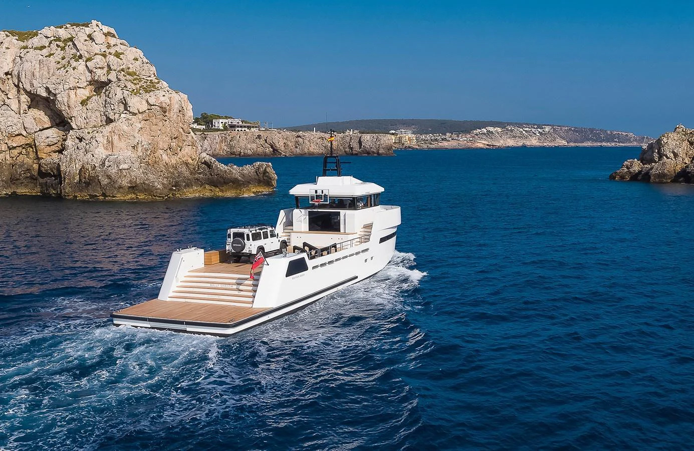 A sleek yacht cruises through clear blue waters near rocky cliffs. aboard 27 YXT Yacht for Sale