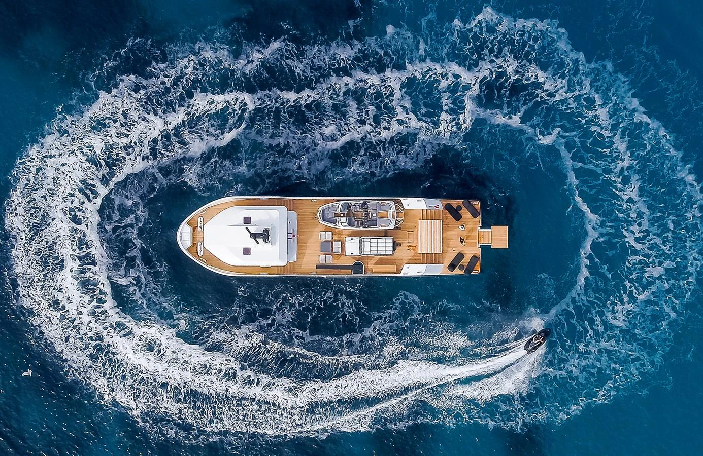 An aerial view of a luxurious yacht cruising through the water, leaving a circular wake behind. aboard 27 YXT Yacht for Sale