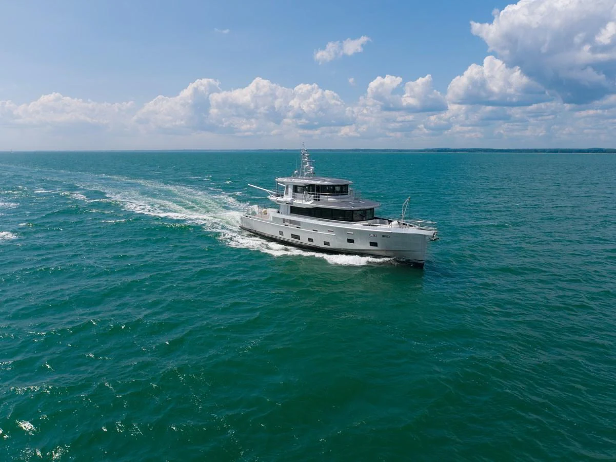 A sleek yacht cruises through open waters under a partly cloudy sky. aboard ARKSEN 85 Yacht for Sale