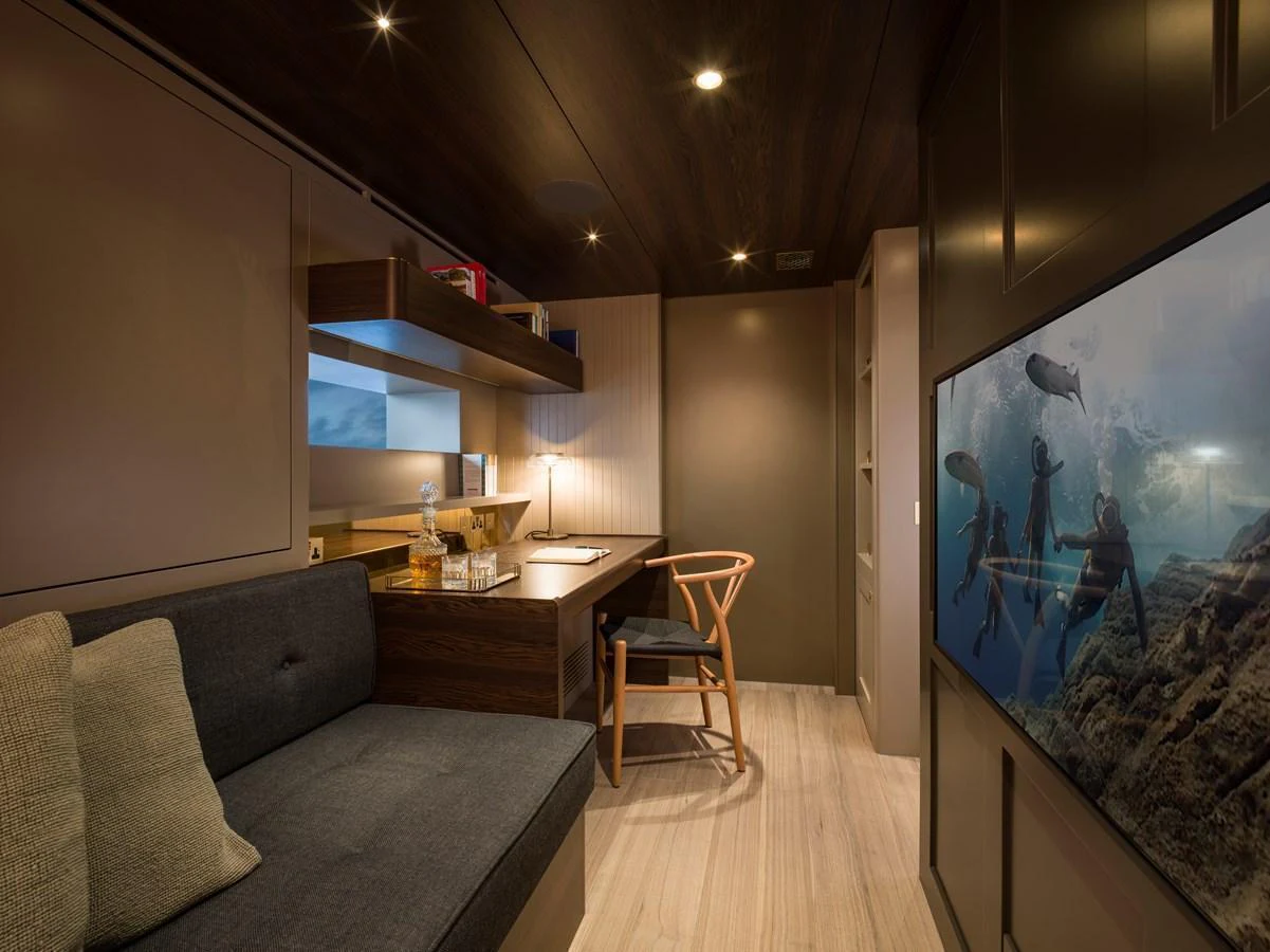 A cozy interior space featuring a desk, sofa, and large TV screen, perfect for relaxation or work. aboard ARKSEN 85 Yacht for Sale