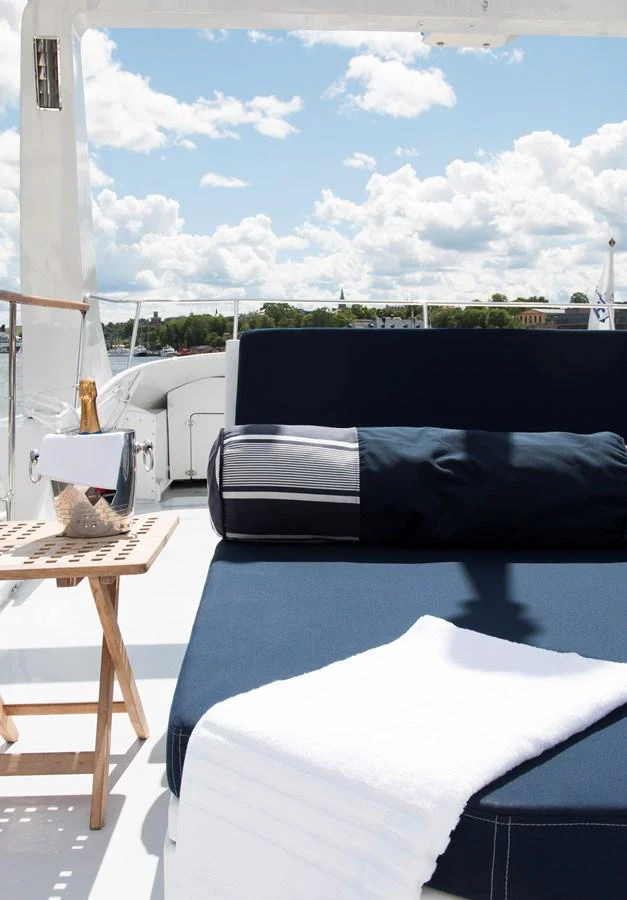 The sundeck features a comfortable lounging area with a bottle of champagne and a towel, perfect for relaxation under the open sky. aboard STELLA NOVA Yacht for Sale
