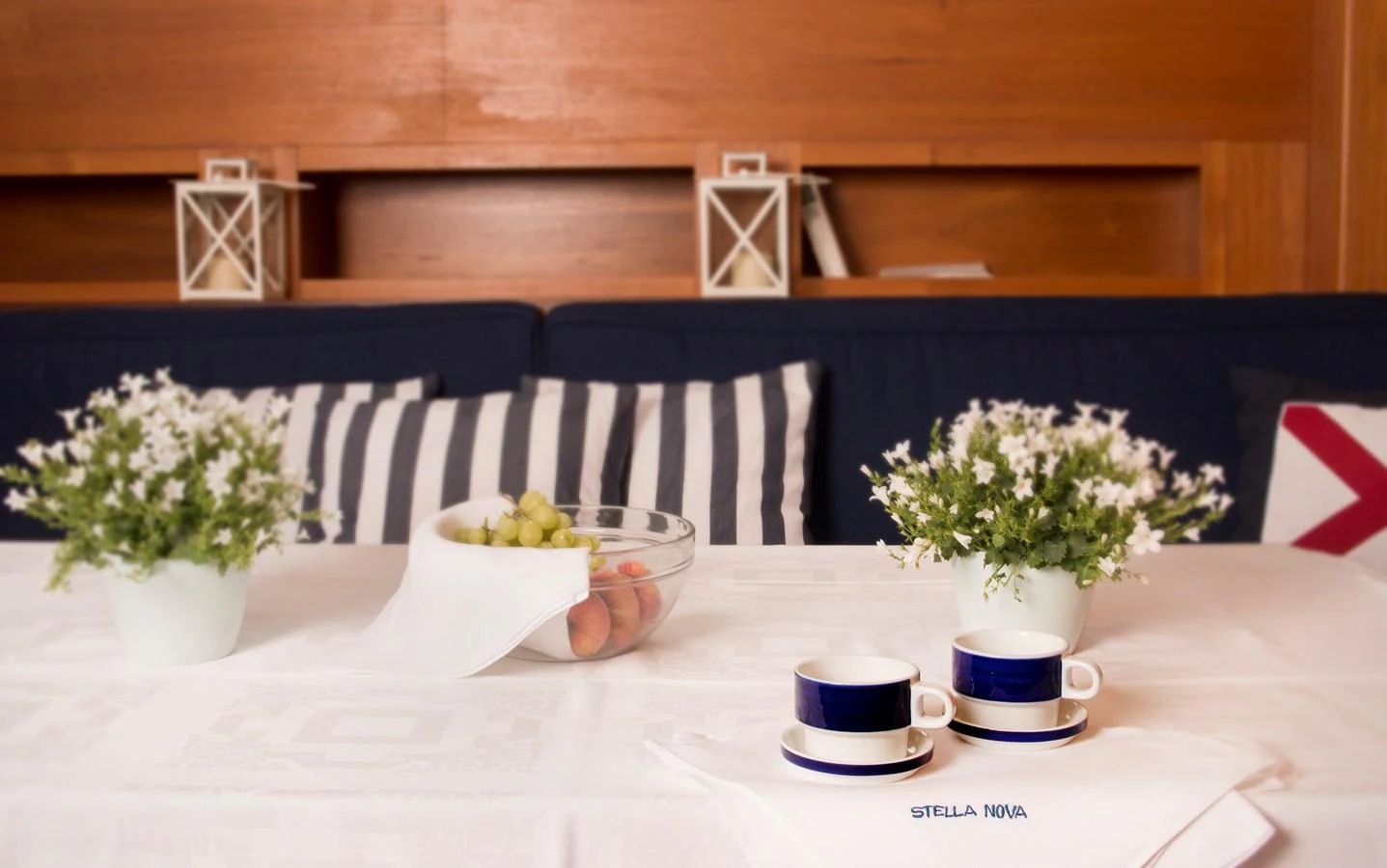 A cozy interior dining area with a neatly set table featuring flowers, fruit, and coffee cups. aboard STELLA NOVA Yacht for Sale