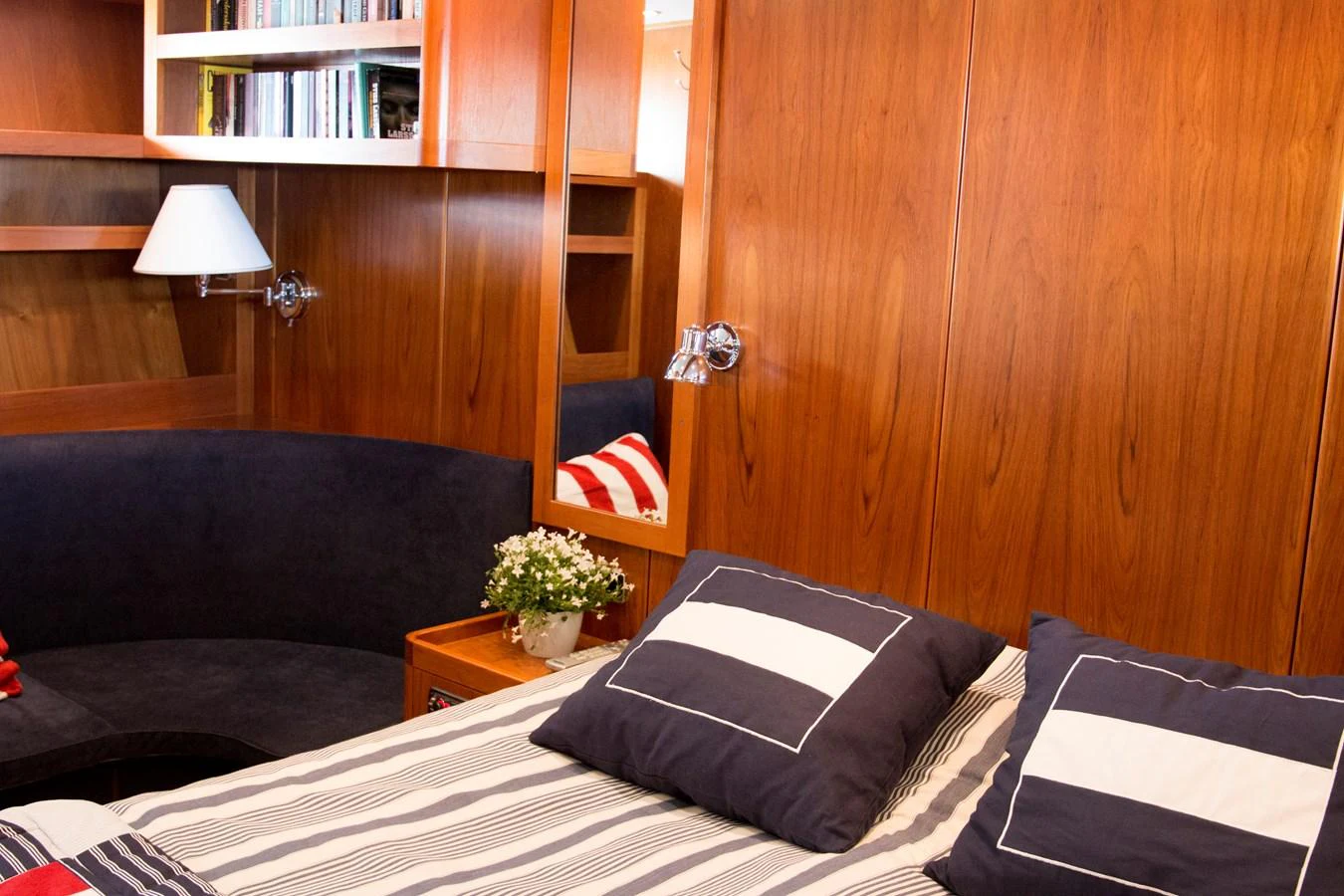 The stateroom features a cozy bed with striped pillows and wood-paneled walls, creating a warm and inviting atmosphere. aboard STELLA NOVA Yacht for Sale