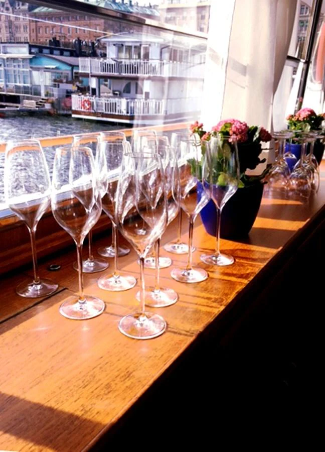 A row of elegant wine glasses is arranged on a wooden surface next to a window with a view of the marina. aboard STELLA NOVA Yacht for Sale