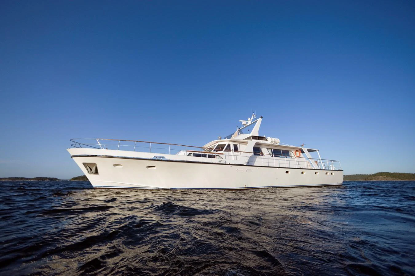 A sleek white yacht glides gracefully on the open water under a clear blue sky. aboard STELLA NOVA Yacht for Sale
