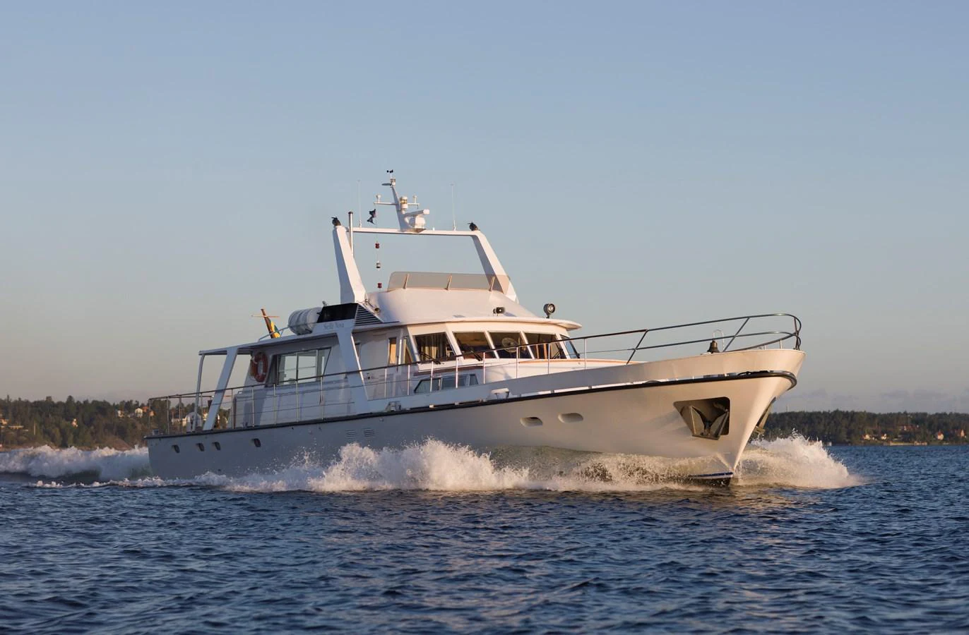 A sleek yacht cruises through calm waters under a clear sky. aboard STELLA NOVA Yacht for Sale