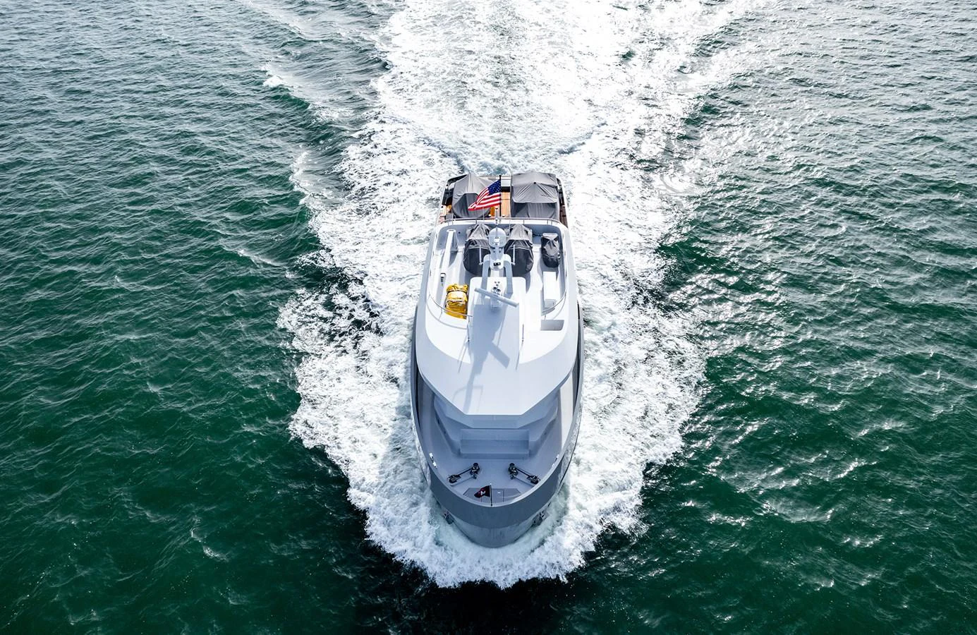 A sleek yacht cruises through the water, leaving a trail of white wake behind. aboard 27 CROSSOVER Yacht for Sale