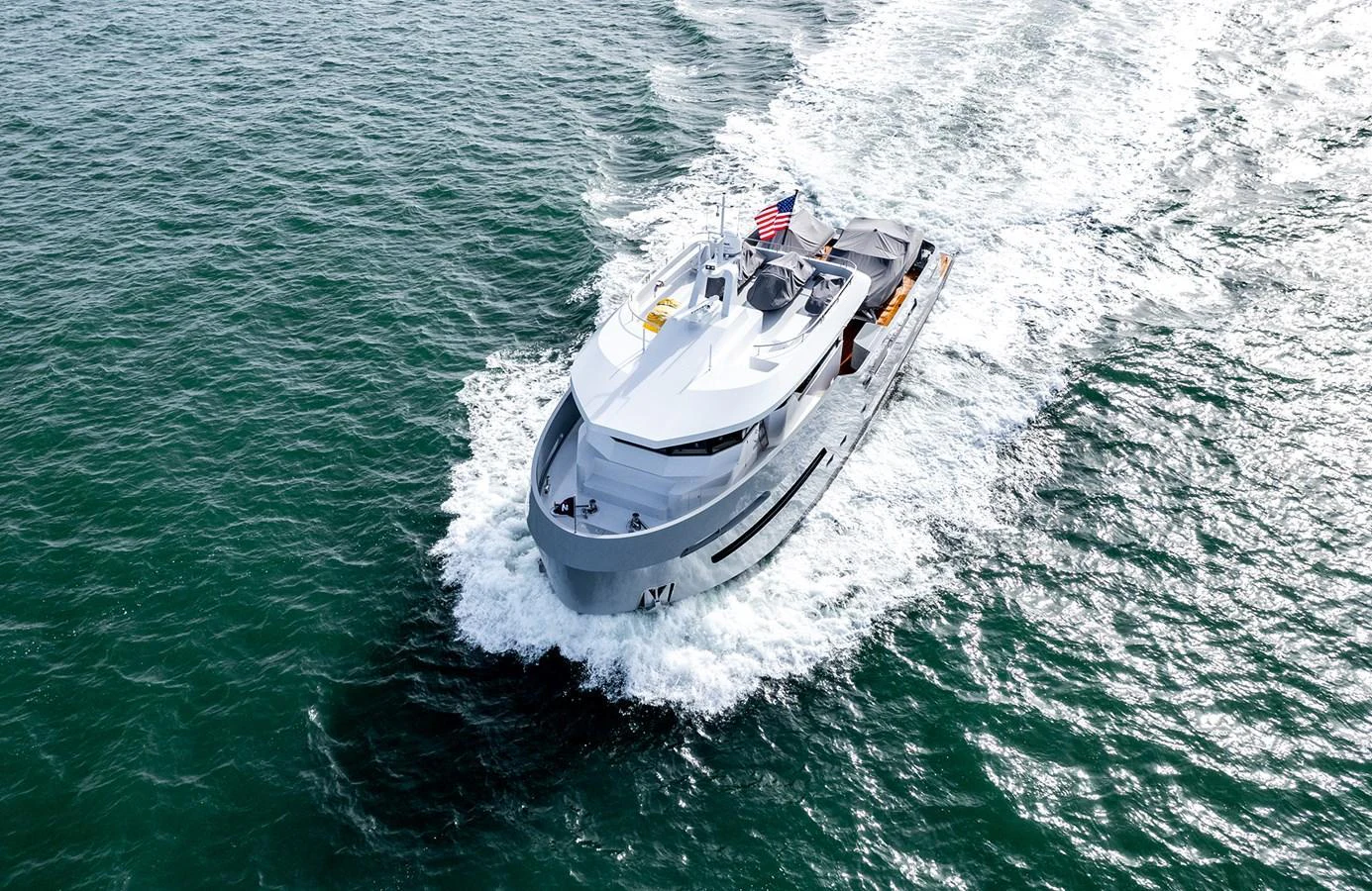 A sleek yacht cruises through the water, leaving a trail of white wake behind. aboard 27 CROSSOVER Yacht for Sale