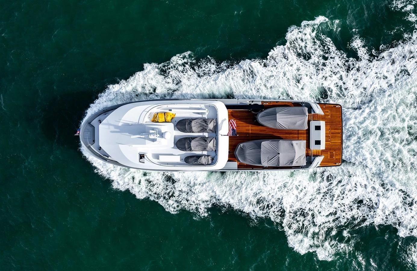 Aerial view of a sleek yacht cruising through the water, showcasing its elegant design and spacious deck. aboard 27 CROSSOVER Yacht for Sale