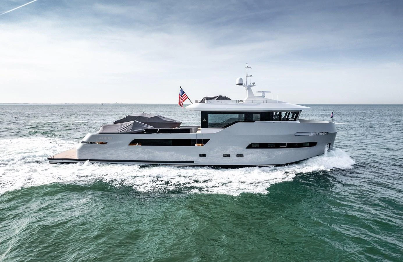 A sleek and modern yacht cruising on open waters with an American flag flying at the stern. aboard 27 CROSSOVER Yacht for Sale