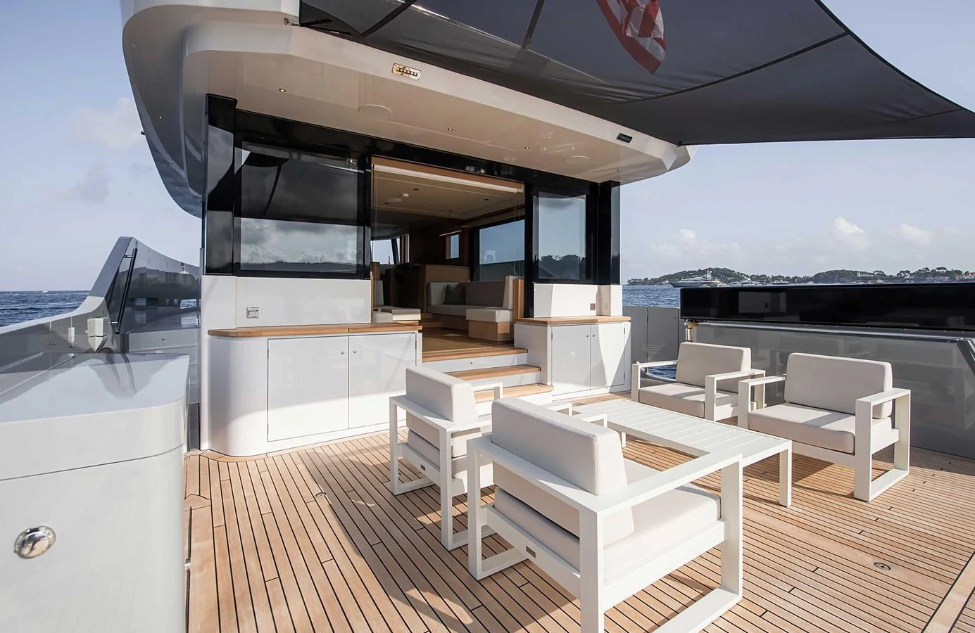 The aft deck features a stylish and spacious outdoor seating area with modern furniture and a shaded canopy. aboard 27 CROSSOVER Yacht for Sale