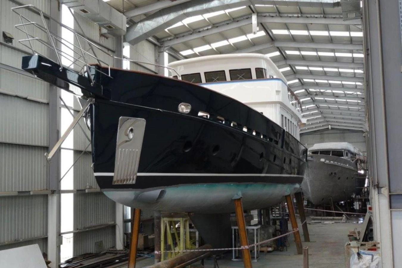 A yacht is under construction in a spacious shipyard, showcasing its sleek design and craftsmanship. aboard SVETLANA Yacht for Sale
