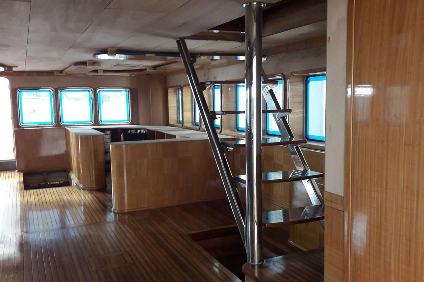 The yacht's salon features polished wooden floors, large windows, and a sleek metal staircase. aboard SVETLANA Yacht for Sale