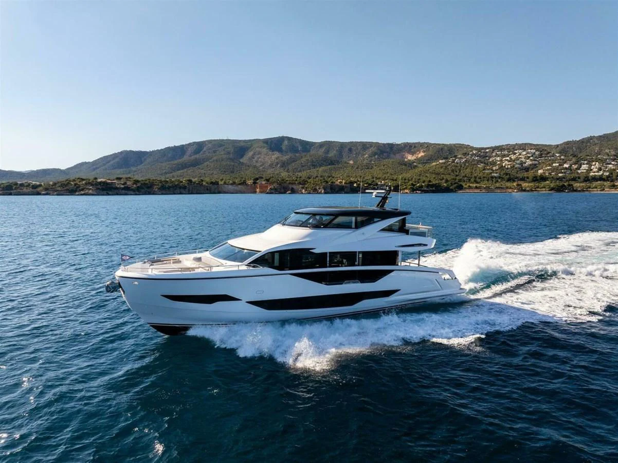 A sleek and modern yacht cruises through clear blue waters with a scenic coastline in the background. aboard 90 OCEAN ENCLOSED Yacht for Sale