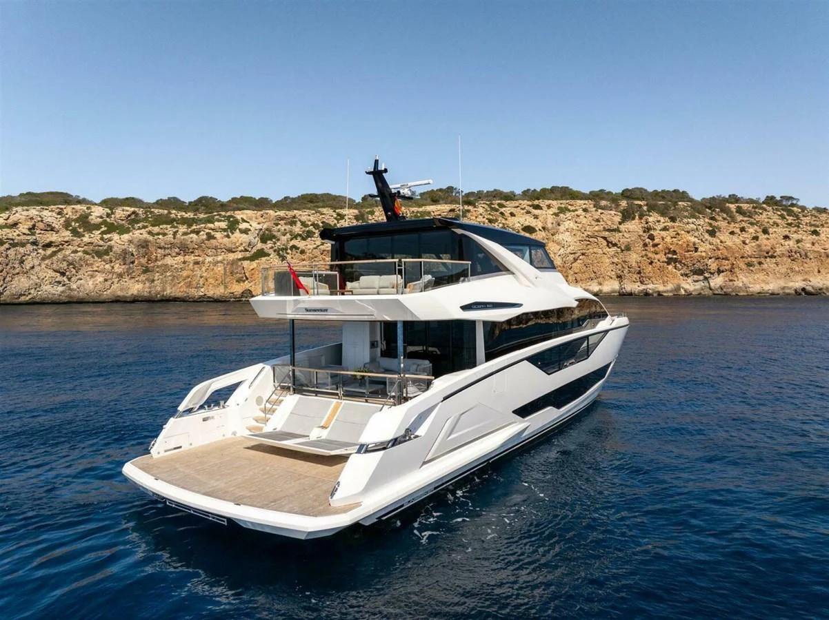 A sleek and modern yacht cruising along a rocky coastline under a clear blue sky. aboard 90 OCEAN ENCLOSED Yacht for Sale