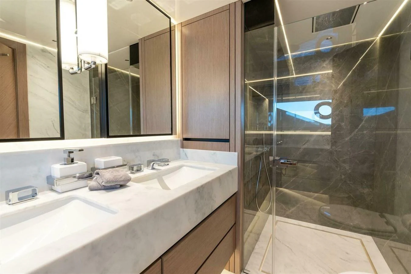 The yacht's bathroom features a luxurious double sink vanity and a spacious glass-enclosed shower. aboard 90 OCEAN ENCLOSED Yacht for Sale